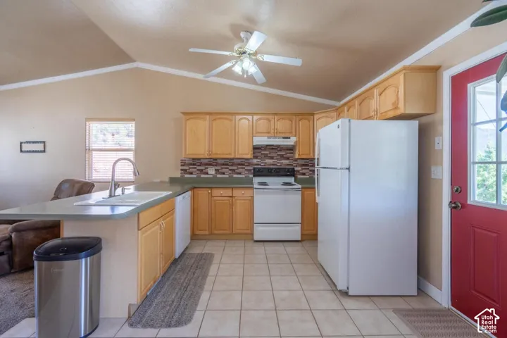 Kitchen featuring a vaulted ceiling, wood-finish cabinetry, tile flooring, and a kitchen island with a sink