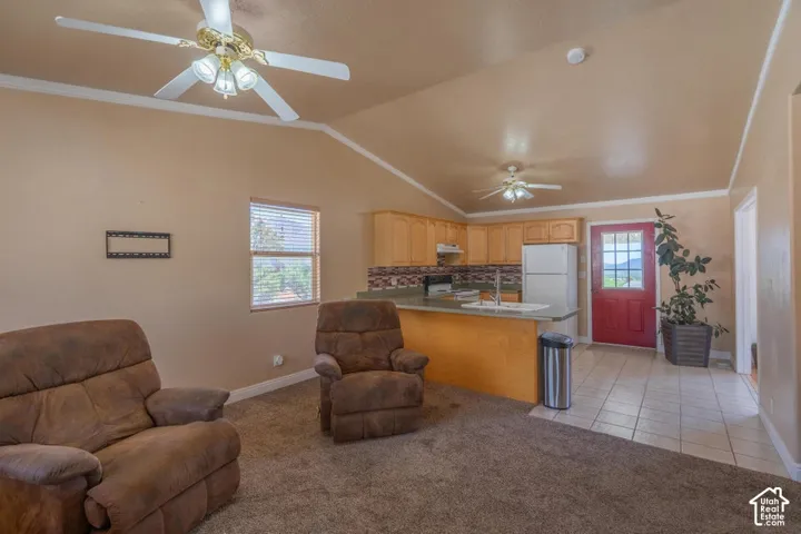 Vaulted ceiling, ceiling fan, natural wood cabinetry, tiled flooring, red paneled door