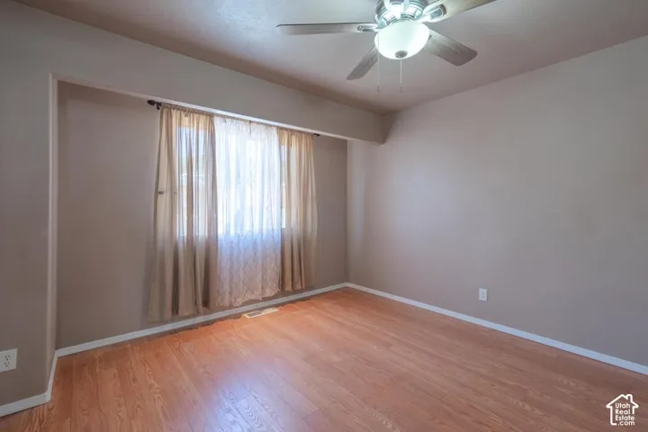 Wood-finish flooring, ceiling fan with integrated lighting, and a recessed window