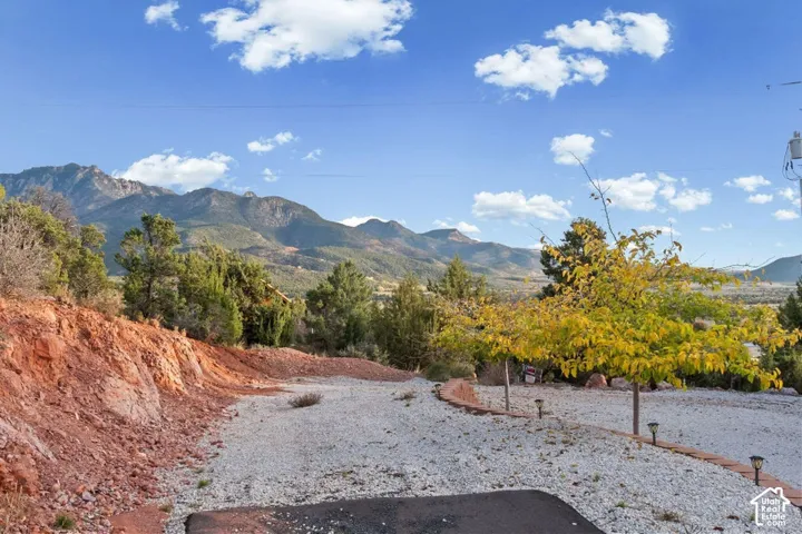 Mountain backdrop with distant peaks, mature trees, and a gravel surface