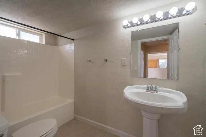 Bathroom featuring a pedestal sink, wall-mounted mirror, and a bathtub with tile surround