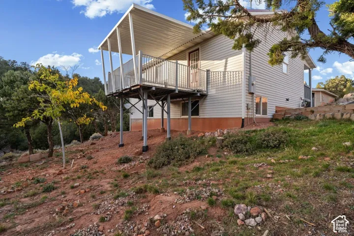 Elevated deck with metal railing, supported by structural pilings, and a covered patio area