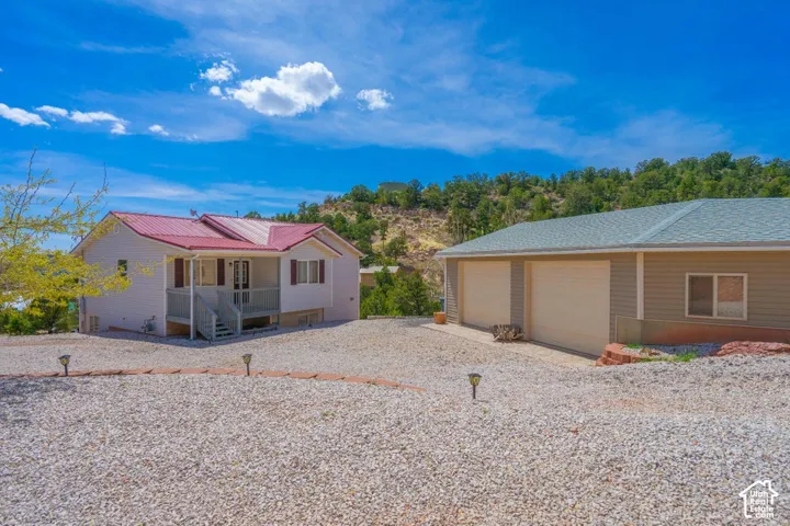 Red metal roof, white siding exterior, covered porch, and a gravel driveway