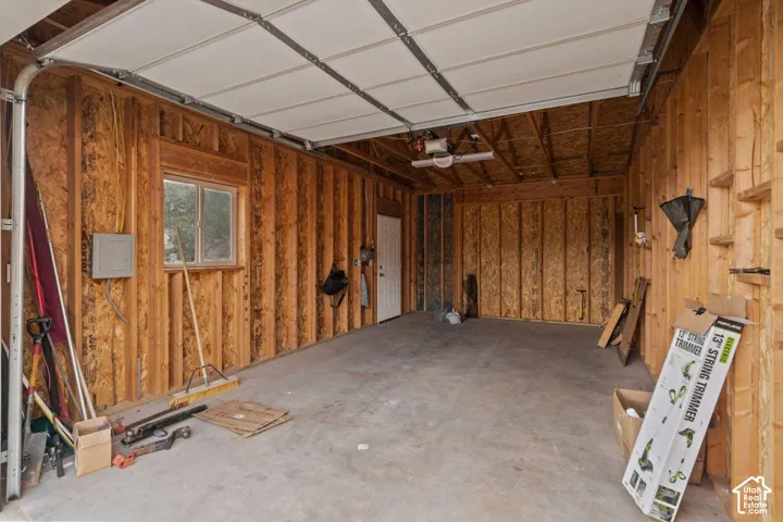 Garage space with exposed wood framing, concrete flooring, and a single window
