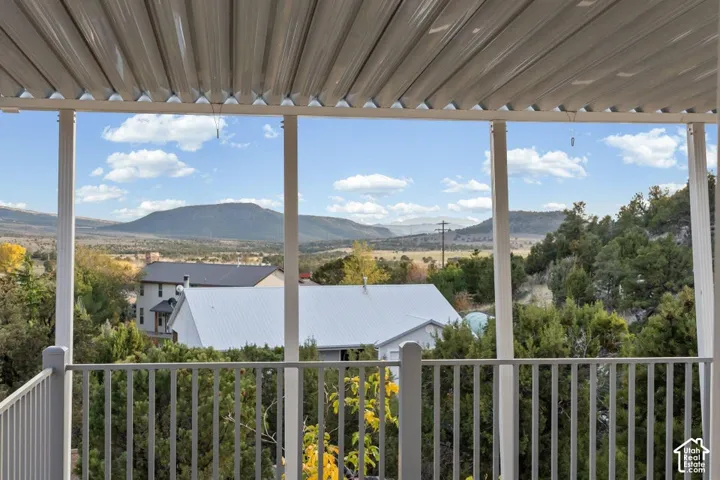 Covered balcony with a metal railing and distant mountain scenery