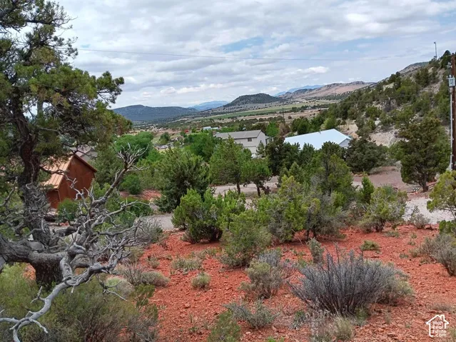 Wood-sided structure with a brown metal roof, set amidst mature trees and natural vegetation