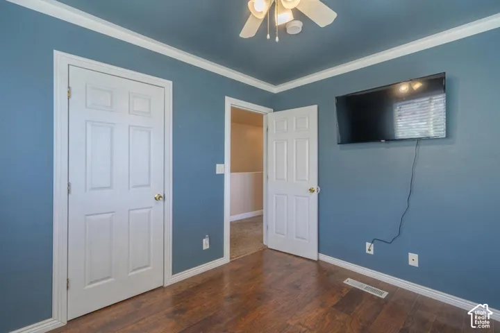 Wood-finish flooring, white trim, crown molding, and a ceiling fan with integrated lighting