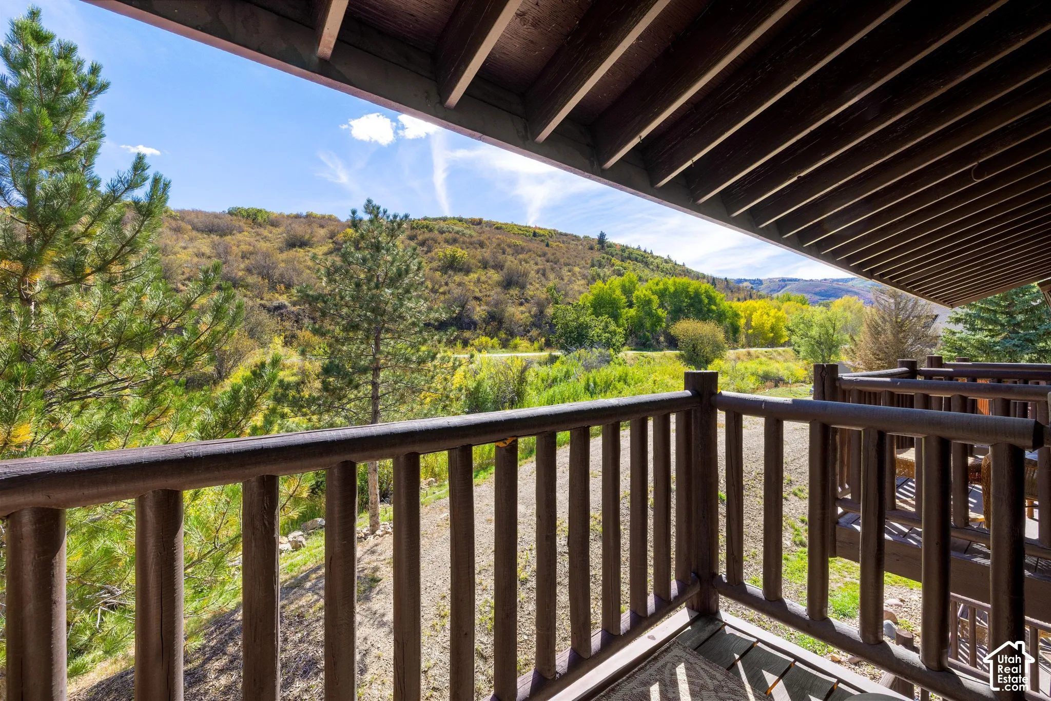 Covered outdoor balcony with wood railings and deck overlooking a natural landscape
