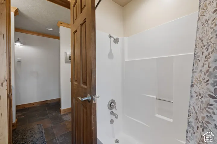 White shower-tub combination with brushed nickel fixtures and a built-in shelf