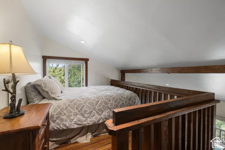 Loft area featuring wood-finish flooring, built-in wooden railing, and a window with natural light