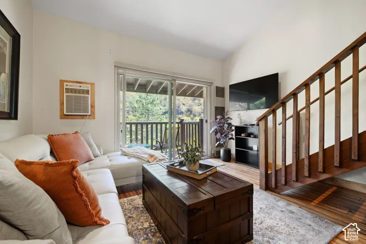 Vaulted ceiling, wood-finish flooring, sliding glass door, private balcony with wood railing, open staircase with wood banister