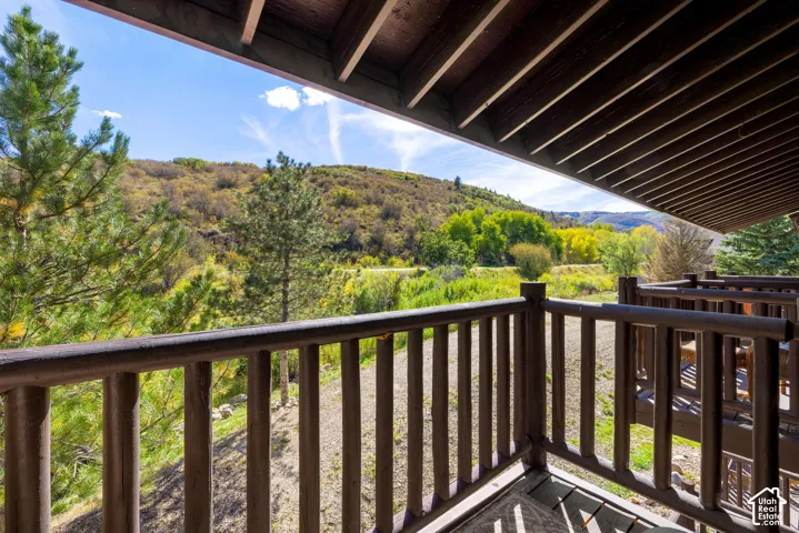 Covered outdoor balcony with wood railings and deck overlooking a natural landscape