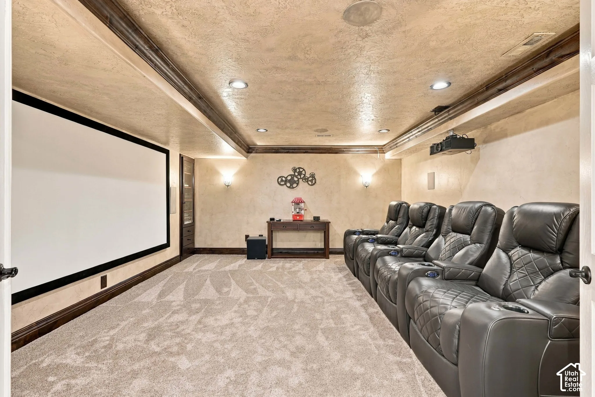Built-in projection screen, recessed lighting, ceiling-mounted projector, wall sconces, and patterned carpeting