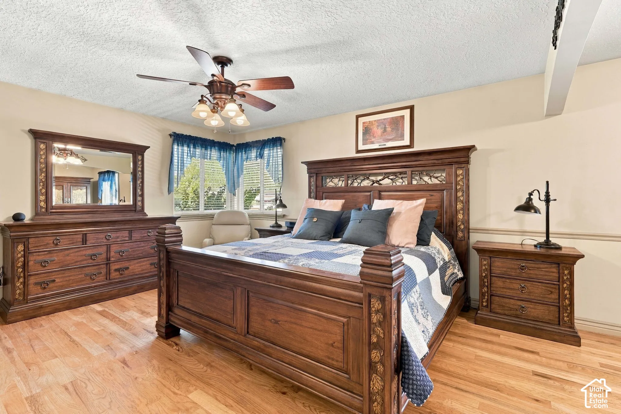 Hardwood flooring, ceiling fan with integrated lighting, multiple windows, neutral wall tones, and crown molding