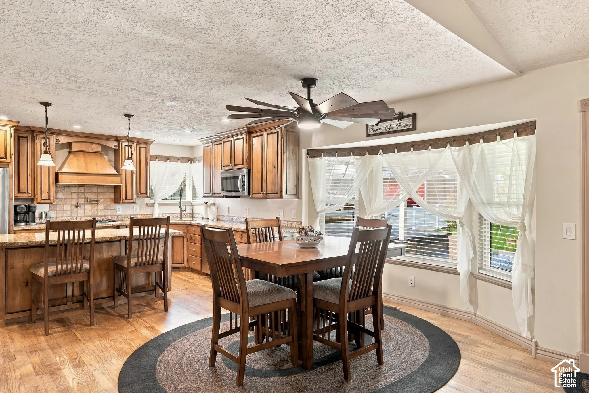 Expansive kitchen with wood-finish flooring, wood cabinetry, stone countertops, and recessed lighting