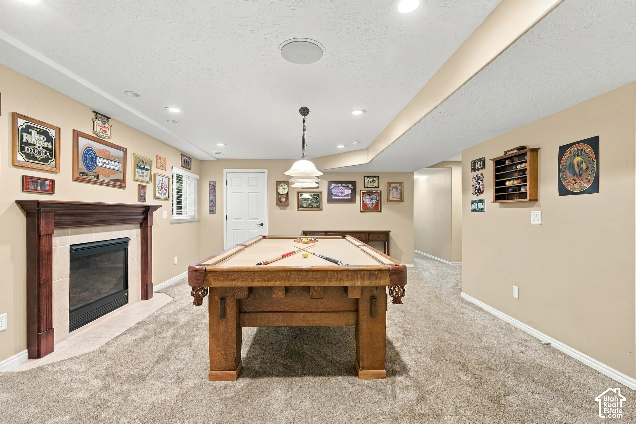 Spacious entertainment area with recessed lighting, an integrated fireplace with a wood mantel, and plush carpet flooring