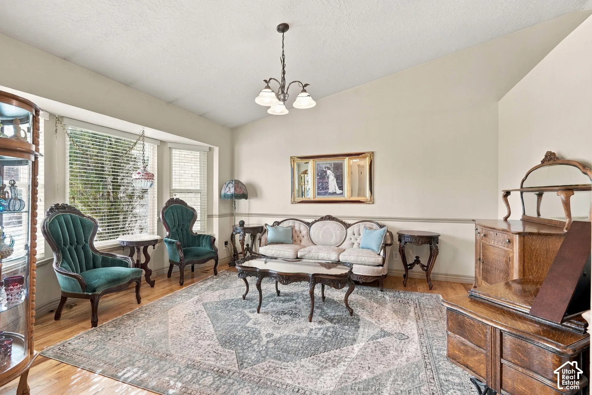 Vaulted ceilings, hardwood flooring, and a decorative chandelier