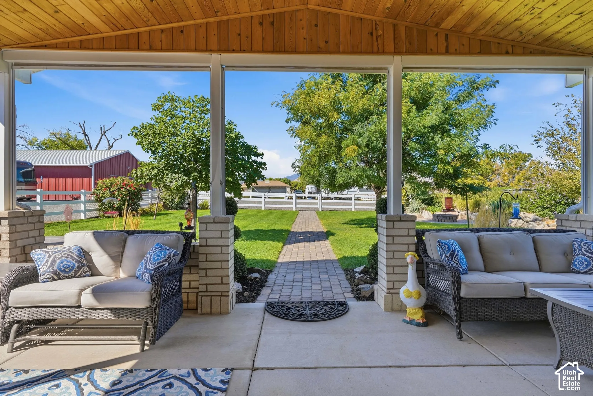 Covered patio with a wood-finish ceiling, brick columns, and concrete flooring