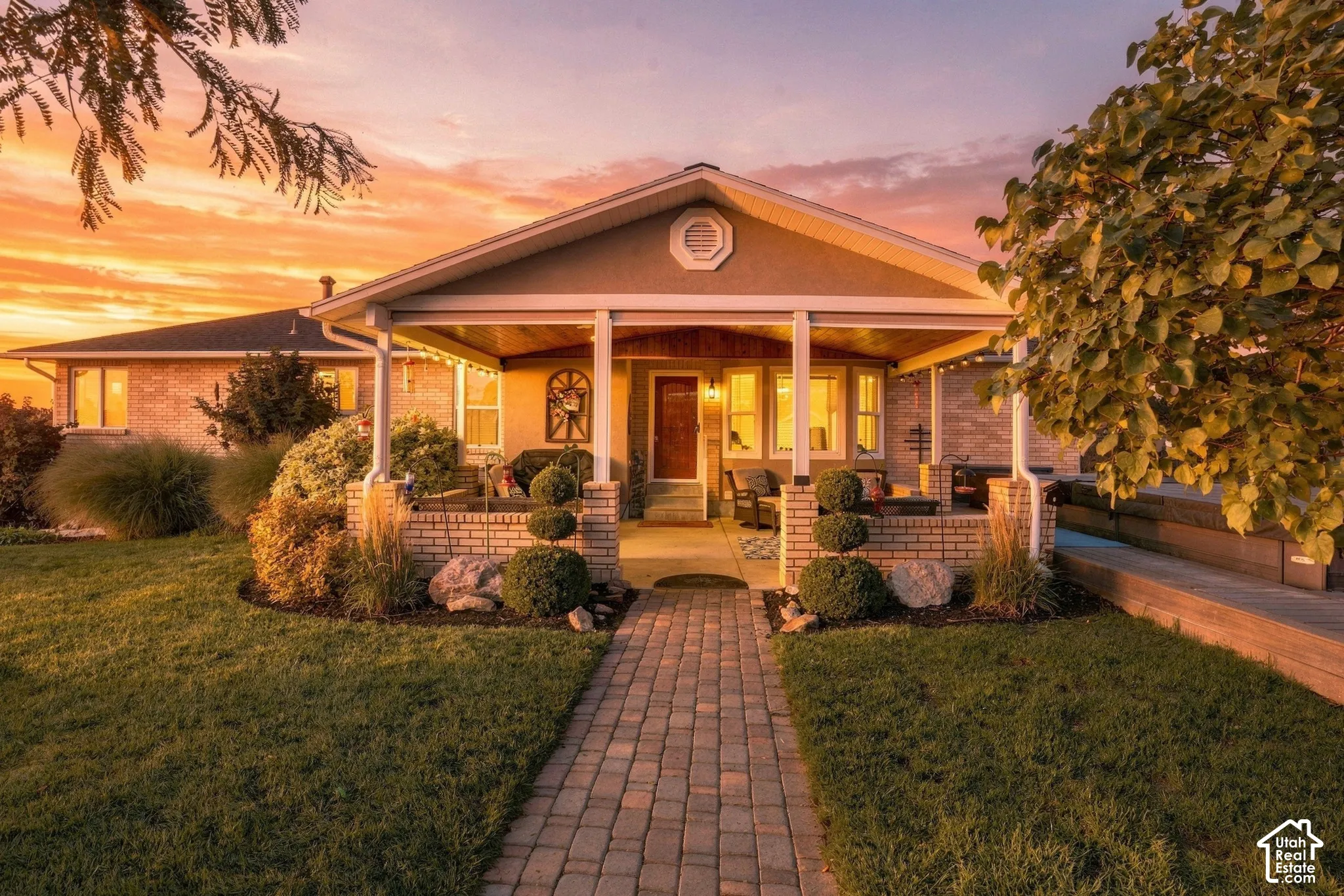 Covered front porch with white columns, brick facade, and a paver walkway