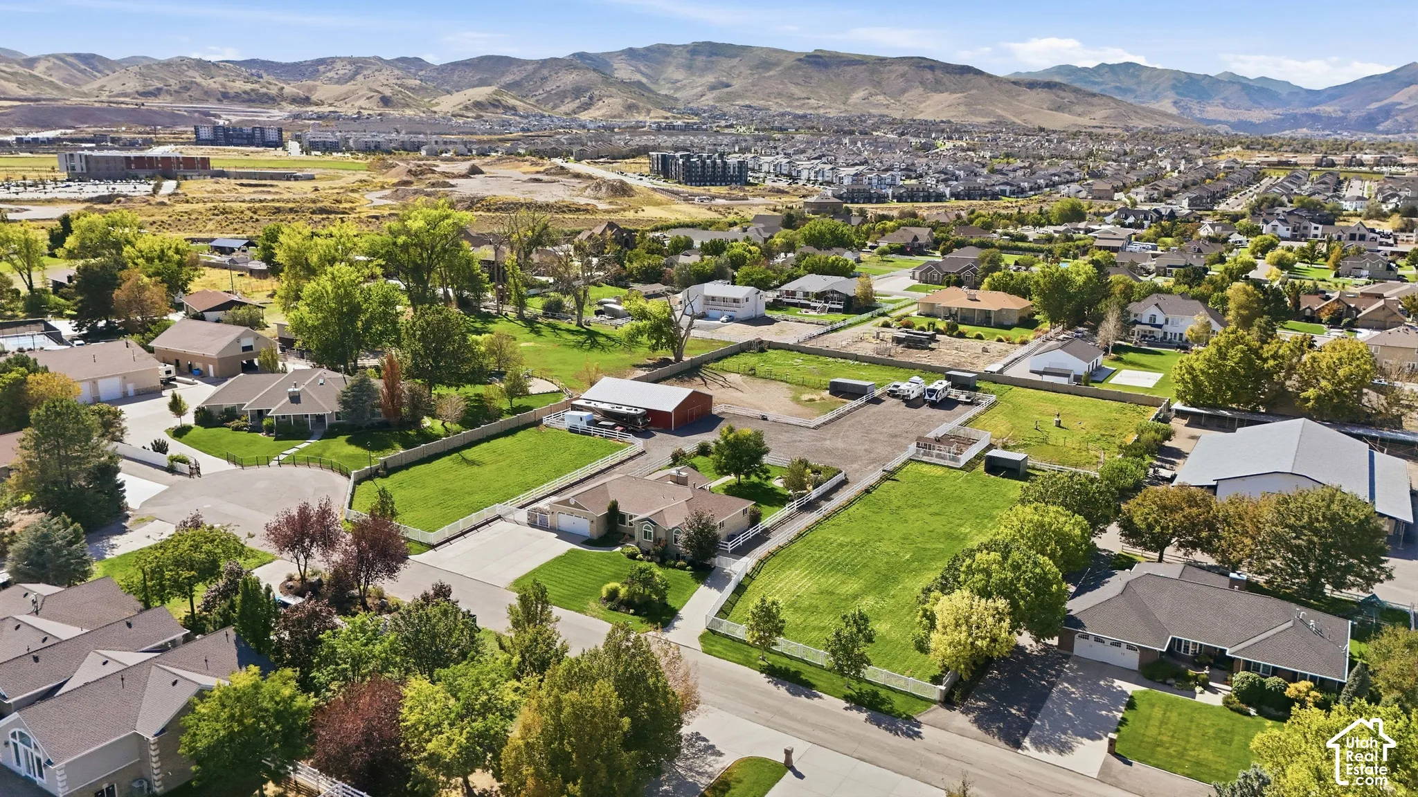 Expansive property featuring a flat, manicured lawn, white picket fencing, and mature trees