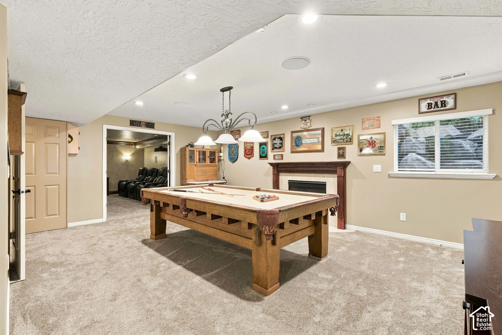 Spacious entertainment room with neutral carpeting, recessed lighting, and a fireplace with a wood-finish mantel