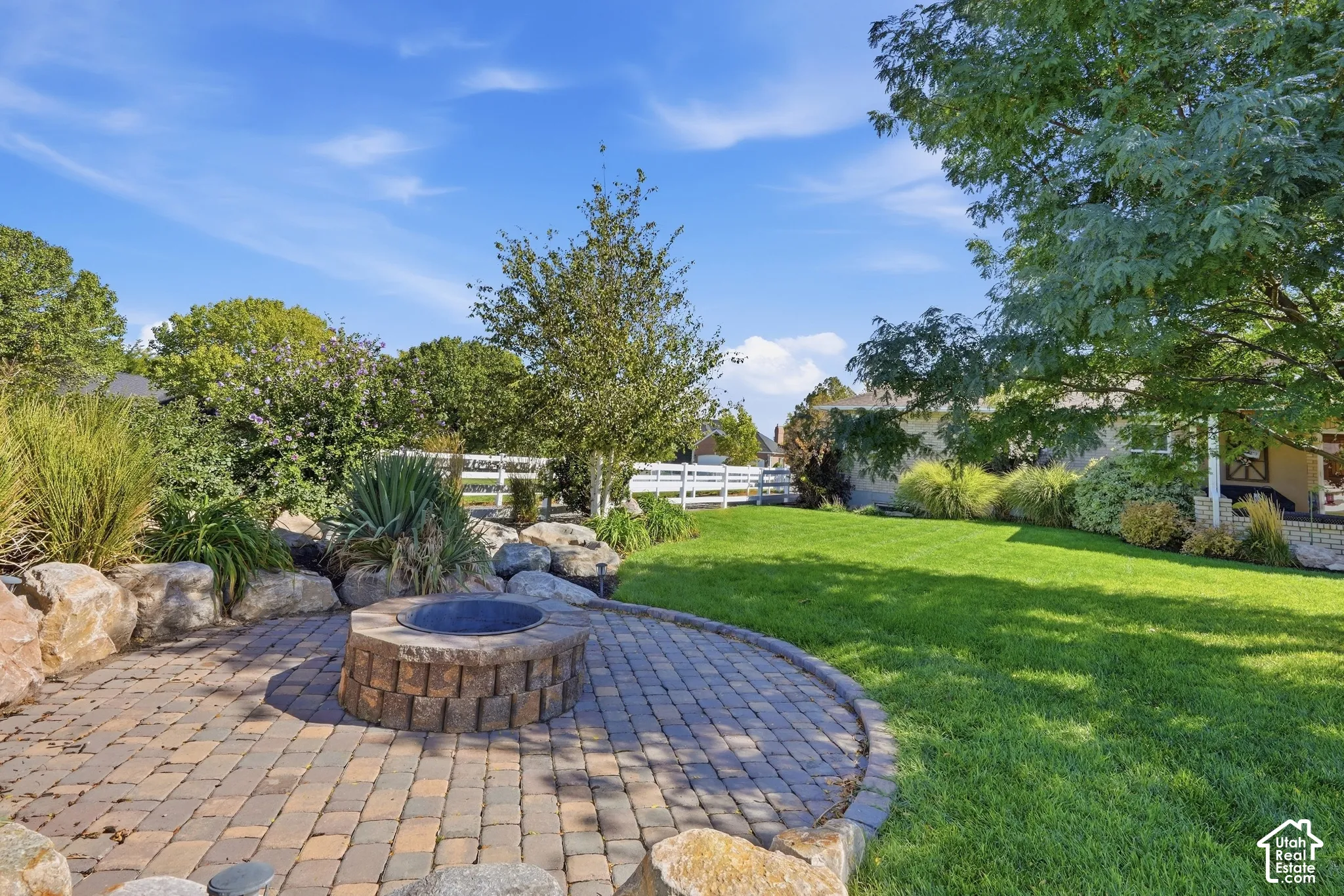 Paver patio with a built-in fire pit, surrounded by natural boulders and landscaping