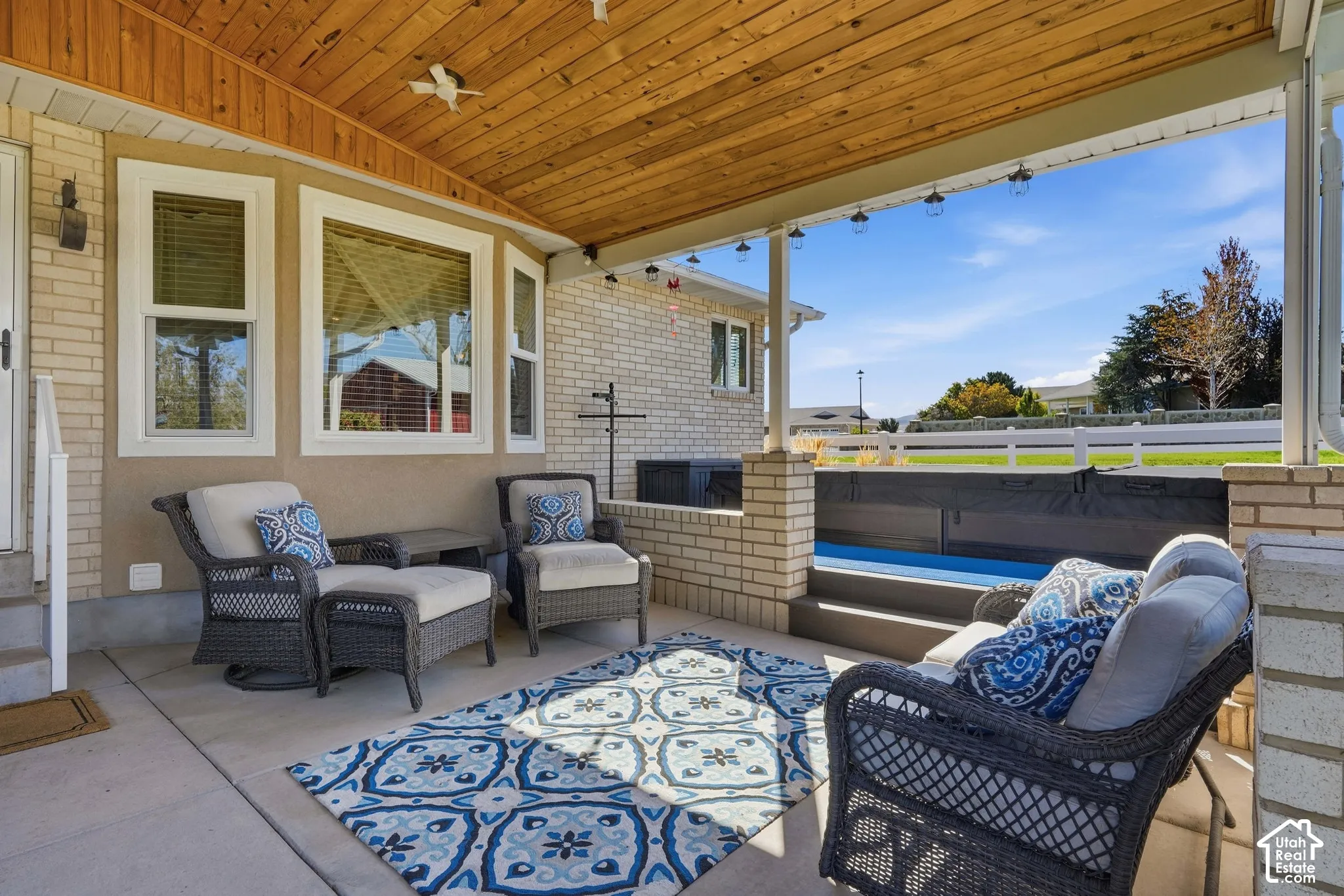 Covered patio with a wood-finish ceiling, exposed brick pillars, and concrete flooring