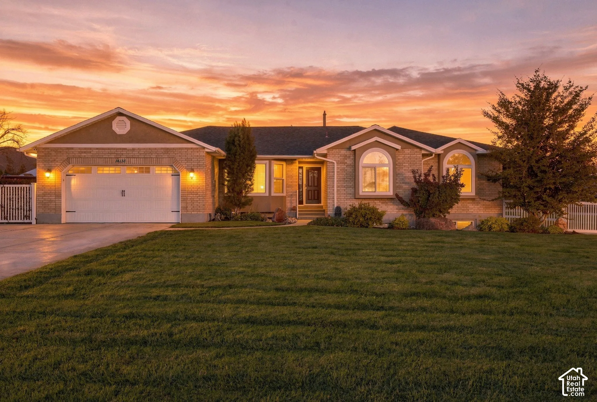Brick and stucco exterior with arched windows, attached garage, and a manicured front lawn