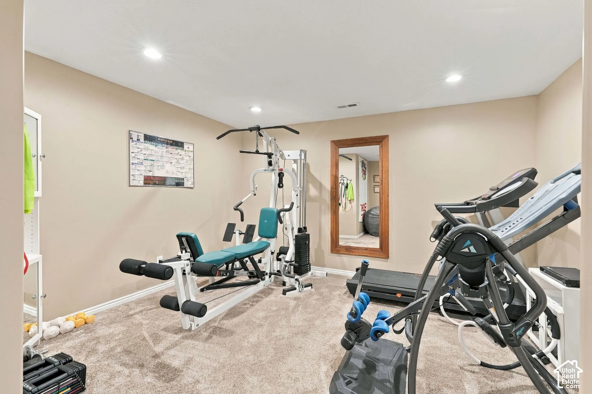 Carpeted room with recessed lighting and a large framed wall mirror