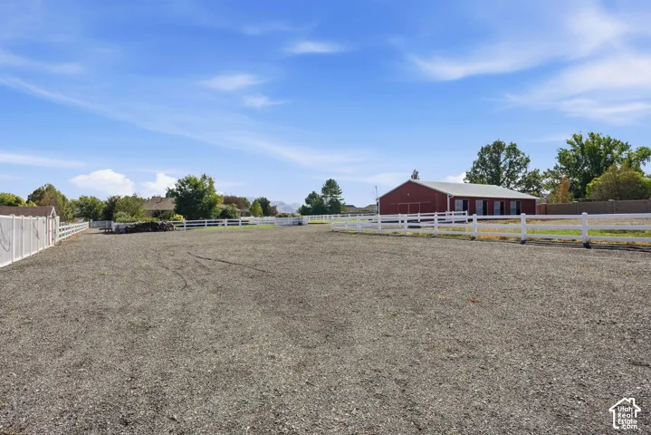 Gravel-surfaced outdoor area with white fencing and a red barn structure