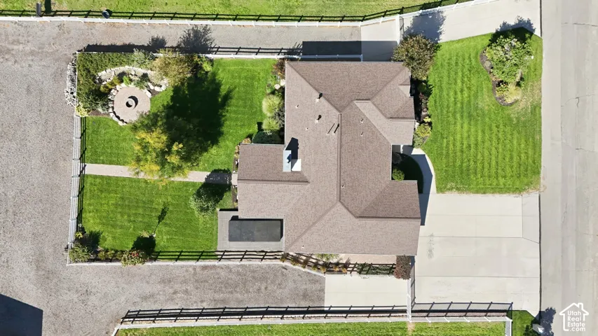 Brown shingle roofing with multiple gables, extensive lawn areas, paved driveway, distinct fire pit area, and a dark-bottom pool