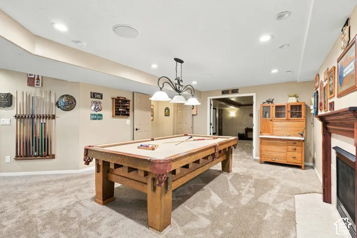Spacious room with recessed lighting and a ceiling-mounted light fixture, featuring carpeted flooring and an integrated fireplace with a mantel