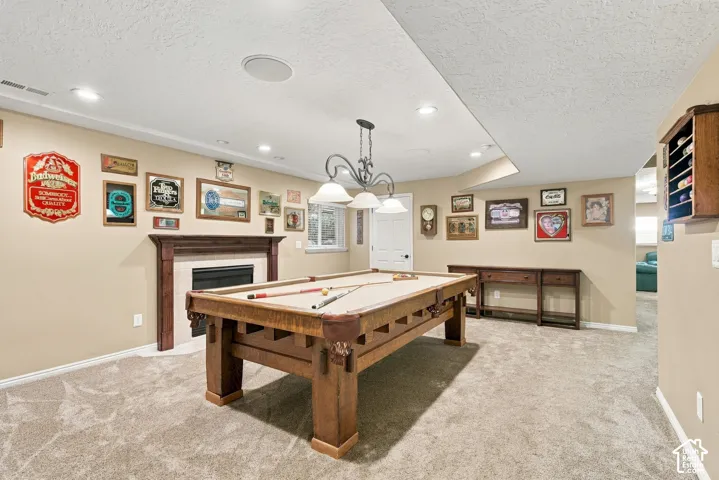 Recessed lighting, wood-finish fireplace surround, white paneled door, light-toned carpet flooring, and ceiling-mounted speakers