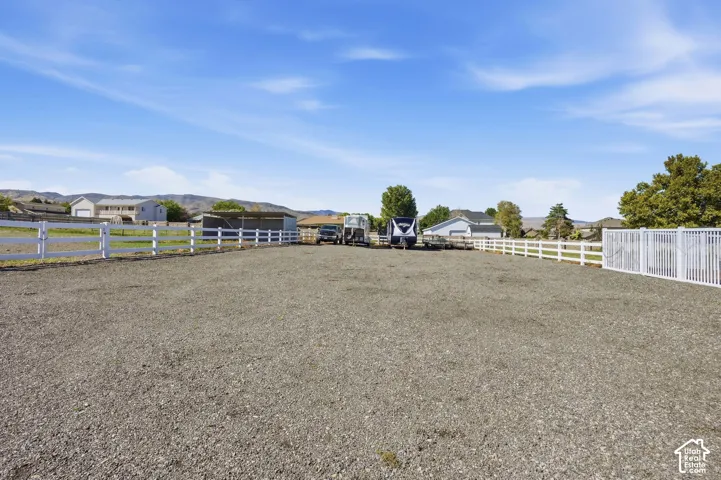 Expansive gravel area with white fencing and a metal outbuilding