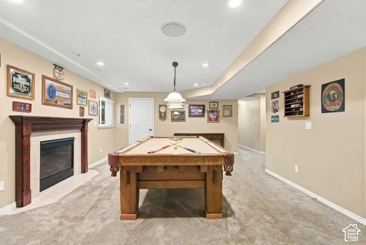 Spacious entertainment area with recessed lighting, an integrated fireplace with a wood mantel, and plush carpet flooring