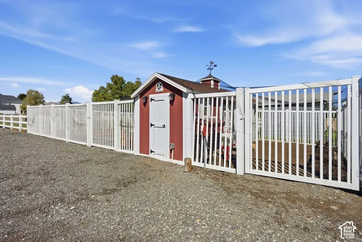 Red and white shed with a cupola and weathervane, bordered by a white picket fence