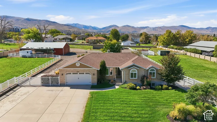 Single-story residence with a two-car garage, established landscaping, and a fenced perimeter