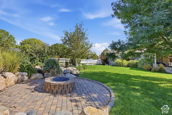 Paver patio with a built-in fire pit, surrounded by natural boulders and landscaping