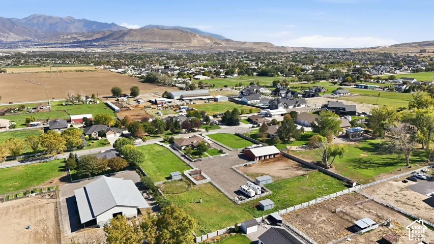 Expansive property with multiple outbuildings, fenced areas, and a large arena, set against a mountain backdrop