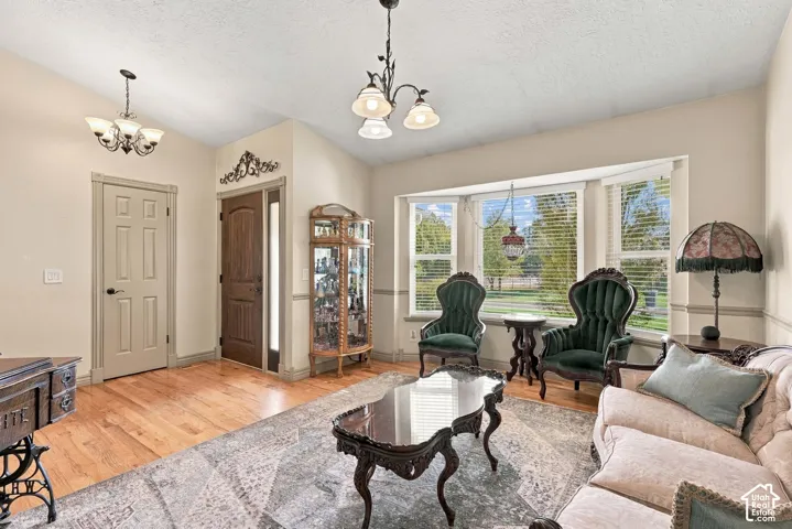 Hardwood flooring, bay window, vaulted ceiling, decorative wall molding, and multiple light fixtures