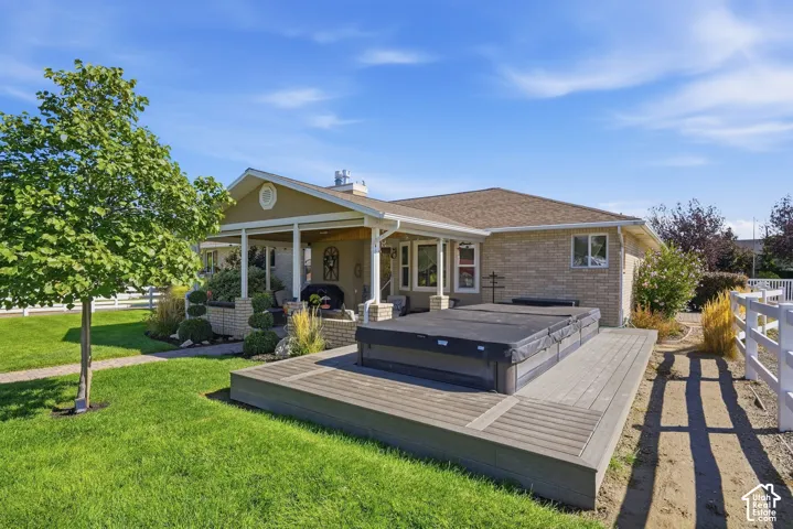 Expansive backyard featuring a large composite deck, covered patio, brick exterior, and white fencing