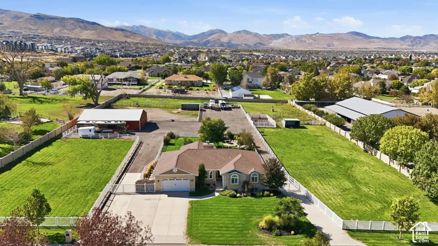 Expansive property featuring a ranch-style residence, detached barn structure, additional covered outbuilding, and mountain backdrop