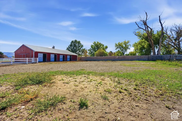 Red barn with white fencing, multiple stalls, and a metal roof