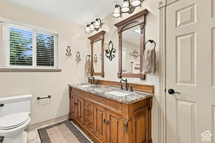 Wood-finish double vanity with integrated sinks, framed mirrors, and wall-mounted light fixtures