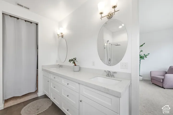 Dual vanity with white cabinetry and integrated sinks, oval mirrors, and wall-mounted light fixtures