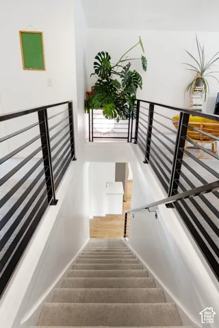 Modern horizontal bar railing, white walls, light-toned wood flooring, and light-toned carpeted stairs