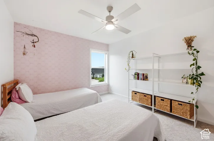 Recessed window, ceiling fan with light fixture, textured accent wall, and light-toned carpeting