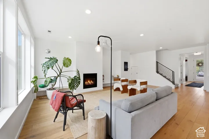 Recessed lighting, light wood-finish flooring, and a modern fireplace with a black surround