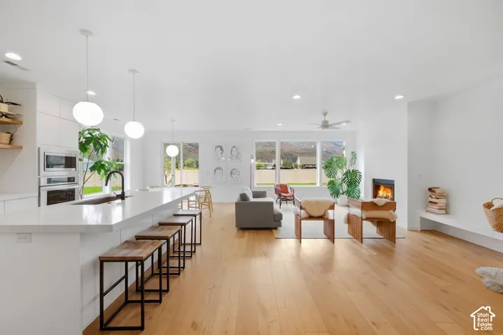 Open concept living area featuring wood-finish flooring, a built-in fireplace, and a kitchen island with pendant lighting