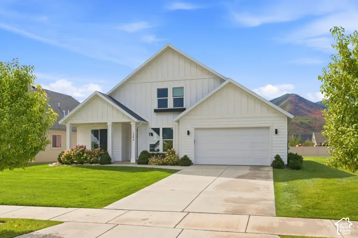 White board-and-batten exterior with a covered entry, attached garage, and landscaped front yard